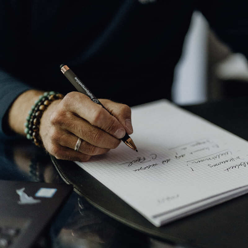 Christoph schreibt während der Ausarbeitung einer Positionierungsstrategie auf einem Blatt Papier mit.